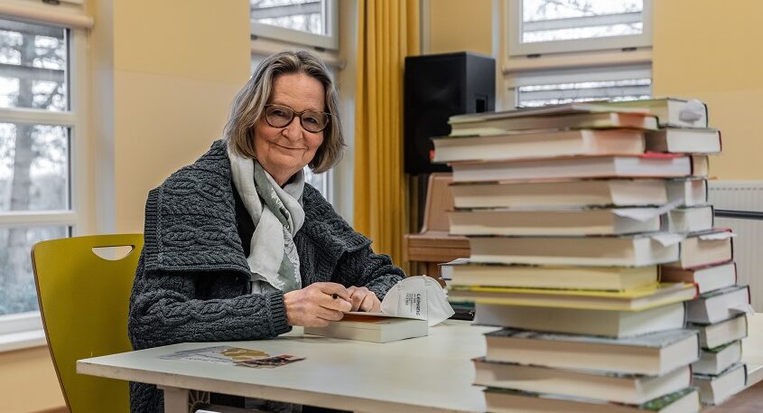 Kirsten Boie lächelt neben Bücherstapel zum Signieren
